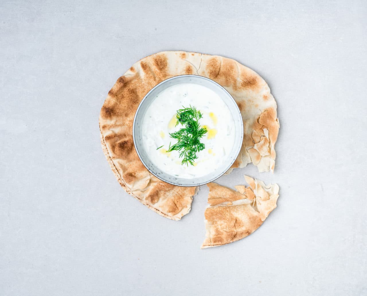 Tzatziki gjort på grekisk yoghurt i en skål ståendes på plattbröd.
