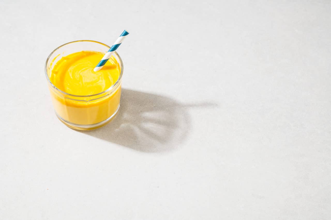 Litet glas med gul smoothie med yoghurt.