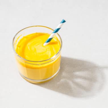 Litet glas med gul smoothie med yoghurt.