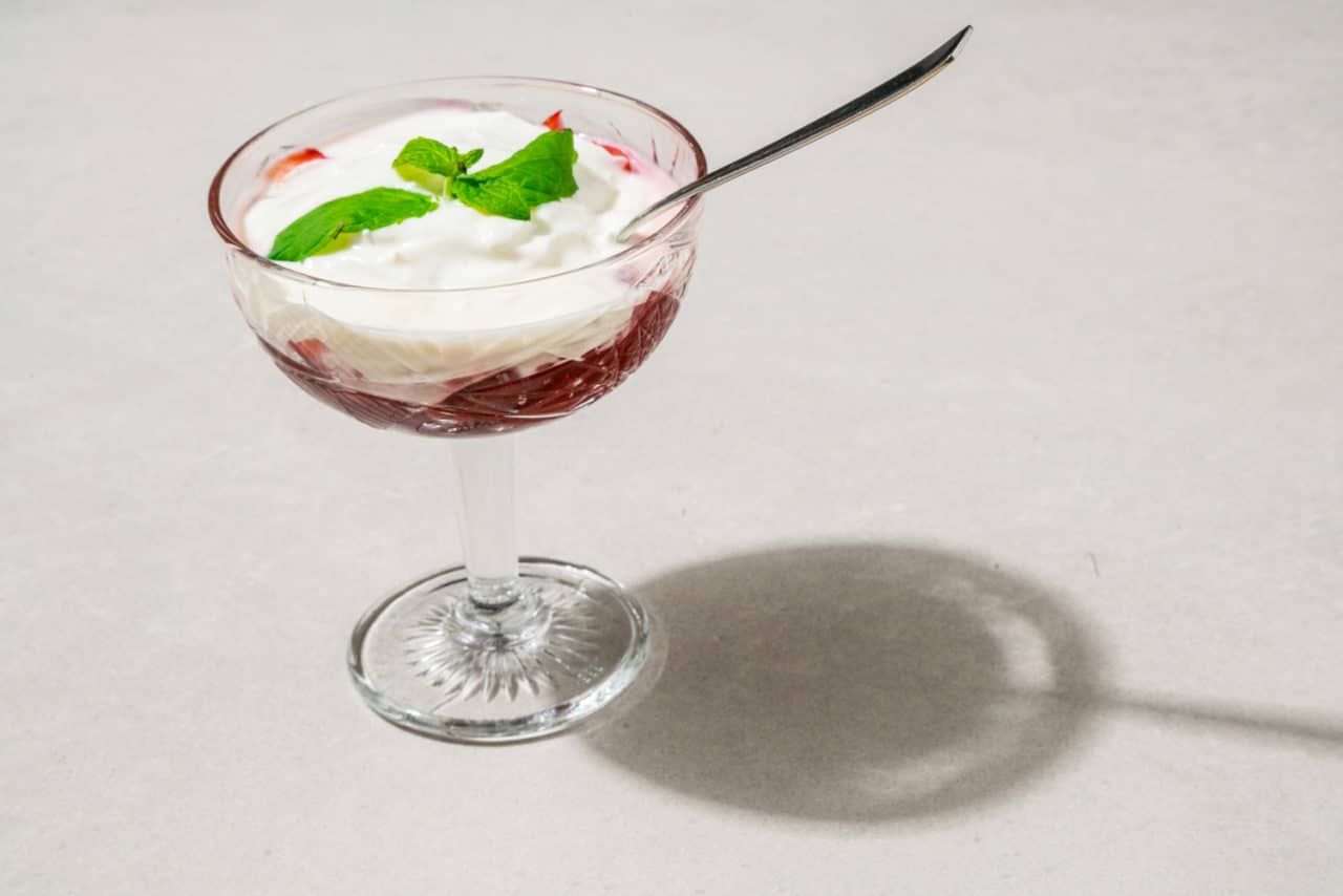 Dessertglas med en röd bärkompott toppad med yoghurt.