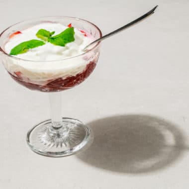 Dessertglas med en röd bärkompott toppad med yoghurt.