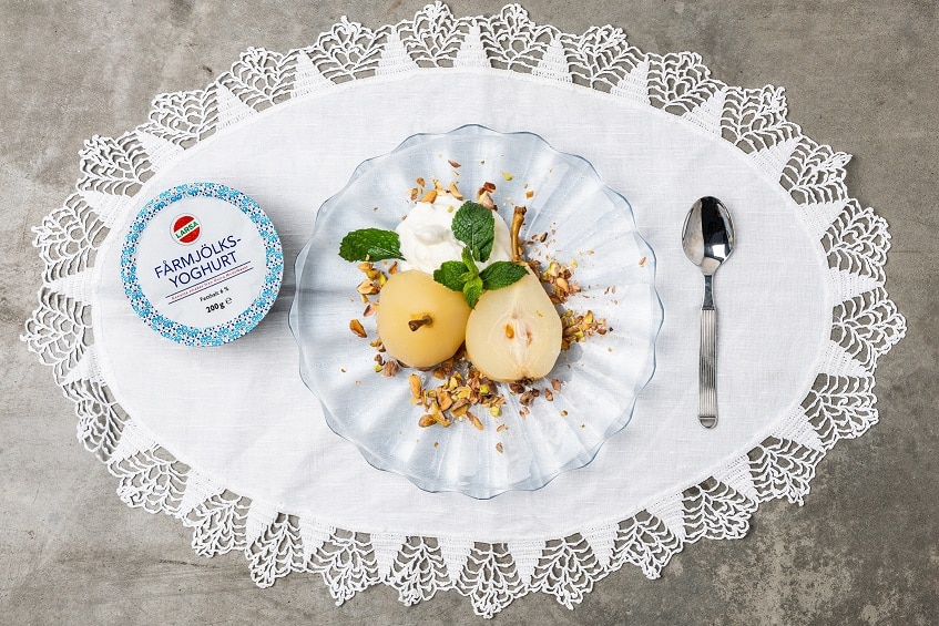 Bakade päron som ligger över en klick yoghurtgrädde