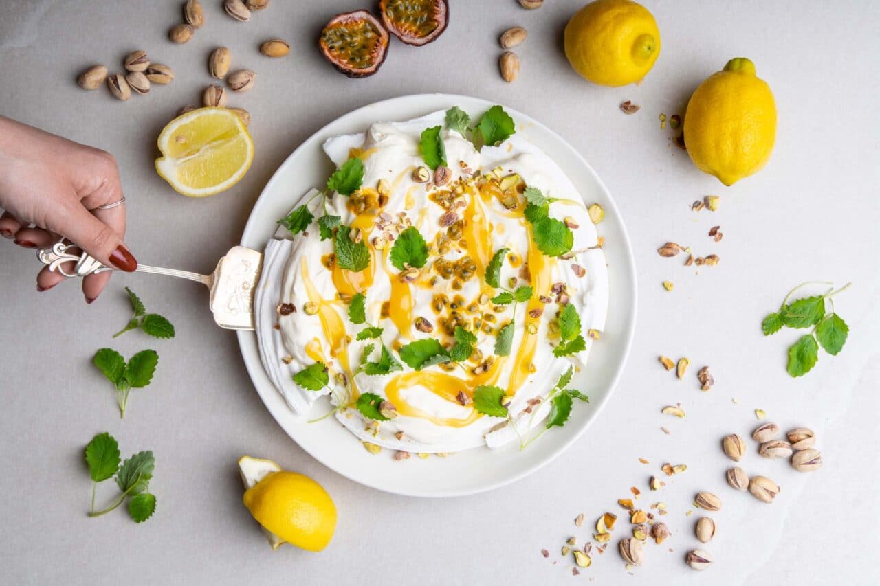 Pavlova med yoghurtgrädde, passionsfrukt och lemon curd från Larsafoods. Serverad med pistagenötter och citronmeliss.